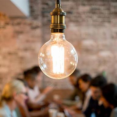 Close up of an industrial looking lightbulb with people sitting in the background